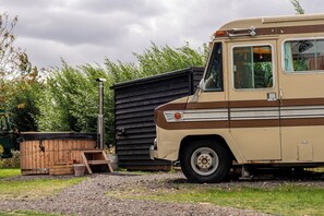 A vintage camper van parked next to a wooden structure, with a gravel path and greenery in the background. - Sleeps 2 -pets Welcome -private Hot Tub -alabama (Skegness)