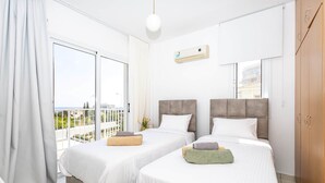 Een hotelkamer met twee bedden, een balkon, een groot raam en een airconditioning.