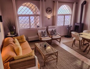 A cozy living room with a sofa, two armchairs, a glass coffee table, and a dining area with a table and chairs. - Amazing Apartment in Algarrobo Campo with Views & Terrace (Algarrobo)
