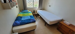 A room with a bed, a small table, a nightstand, a dresser, and a window with curtains. - Amazing Apartment in Algarrobo Campo with Views & Terrace (Algarrobo)