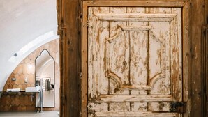 Una porta di legno rustica con uno specchio e un bagno con lavandino e porta asciugamani.