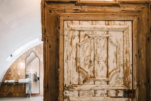 A rustic wooden door with a mirror and a bathroom with a sink and towel rack. - Il Granile Contemporary Loft  (Matera)