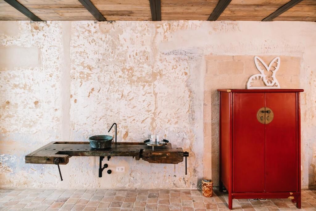 Una cocina rústica con una mesa de madera, un armario rojo y un conejo decorativo colgado en la pared.