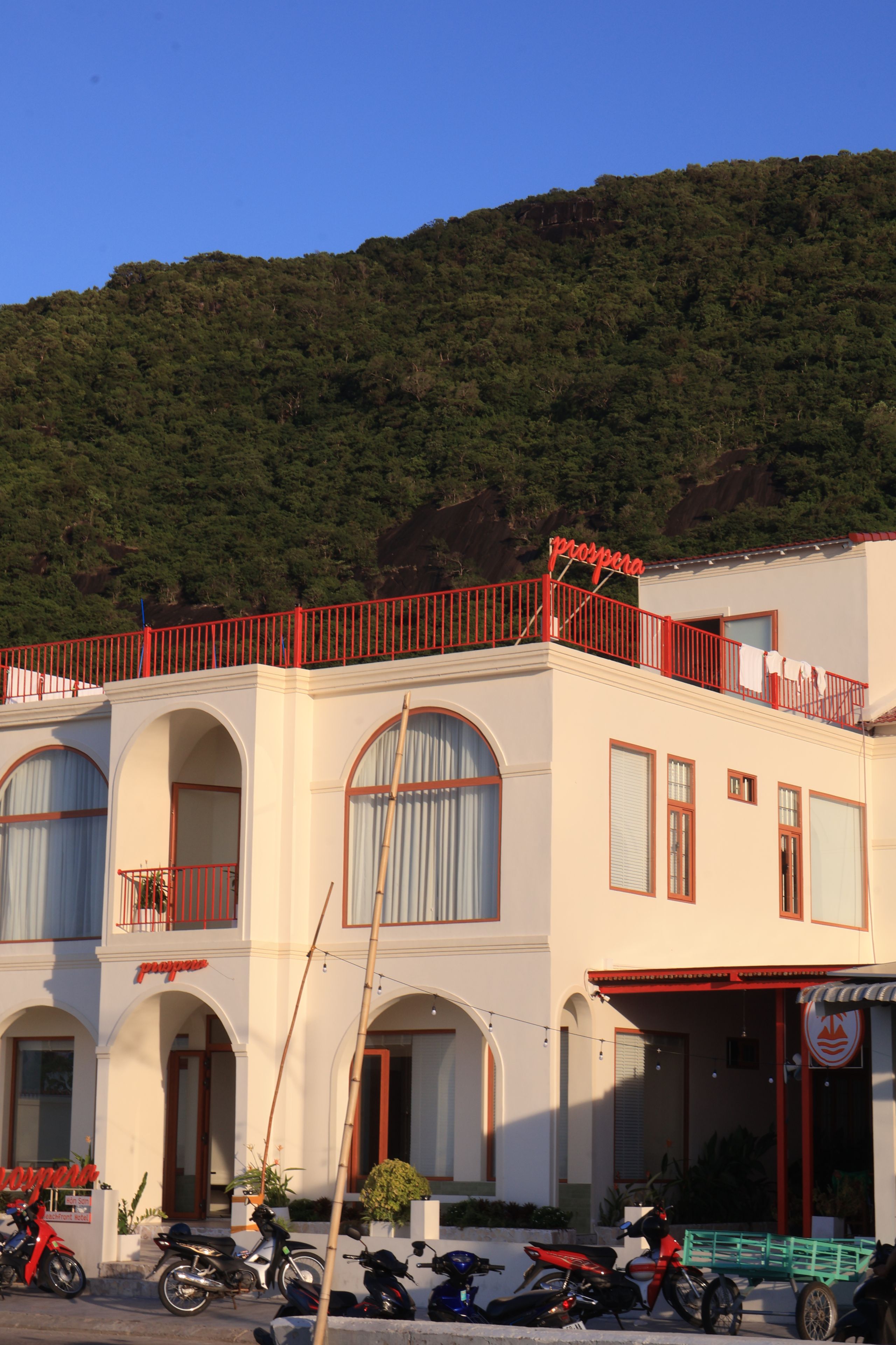 Un bâtiment doté d’un balcon rouge, de fenêtres en arc de cercle et d’une enseigne sur laquelle on peut lire le mot « prospera ».