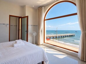 A hotel room with a large window offering a view of the sea and a pier.