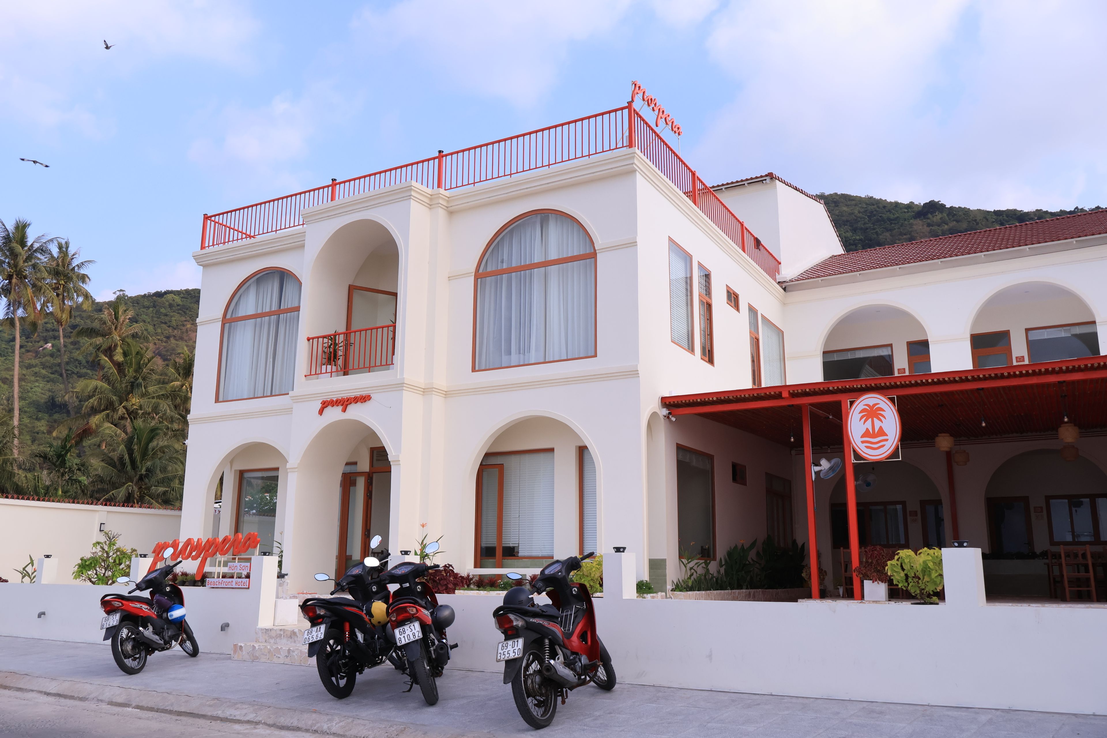 A two-story building with a red balcony and arched windows, labeled as a hotel.