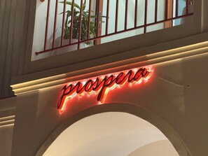 A neon sign with the word 'prospera' in cursive letters.