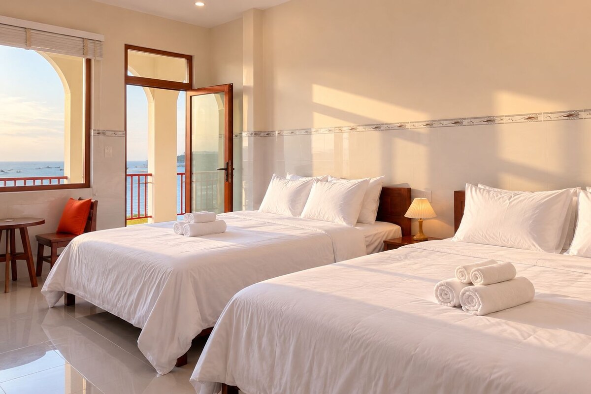 A hotel room with two beds, a balcony, and a view of the sea.