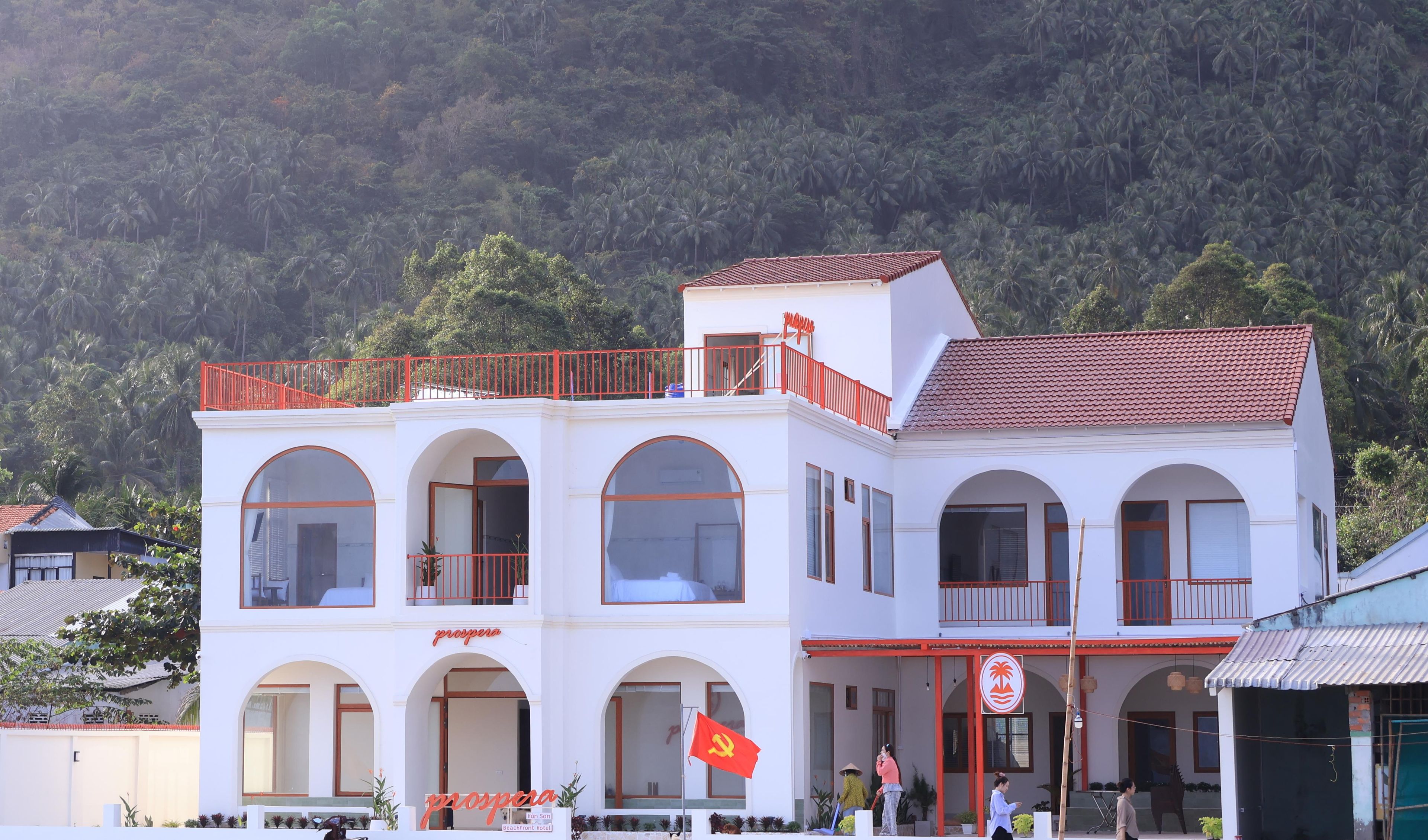 Un edificio de dos pisos con ventanas arqueadas y barandal de balcón rojo.