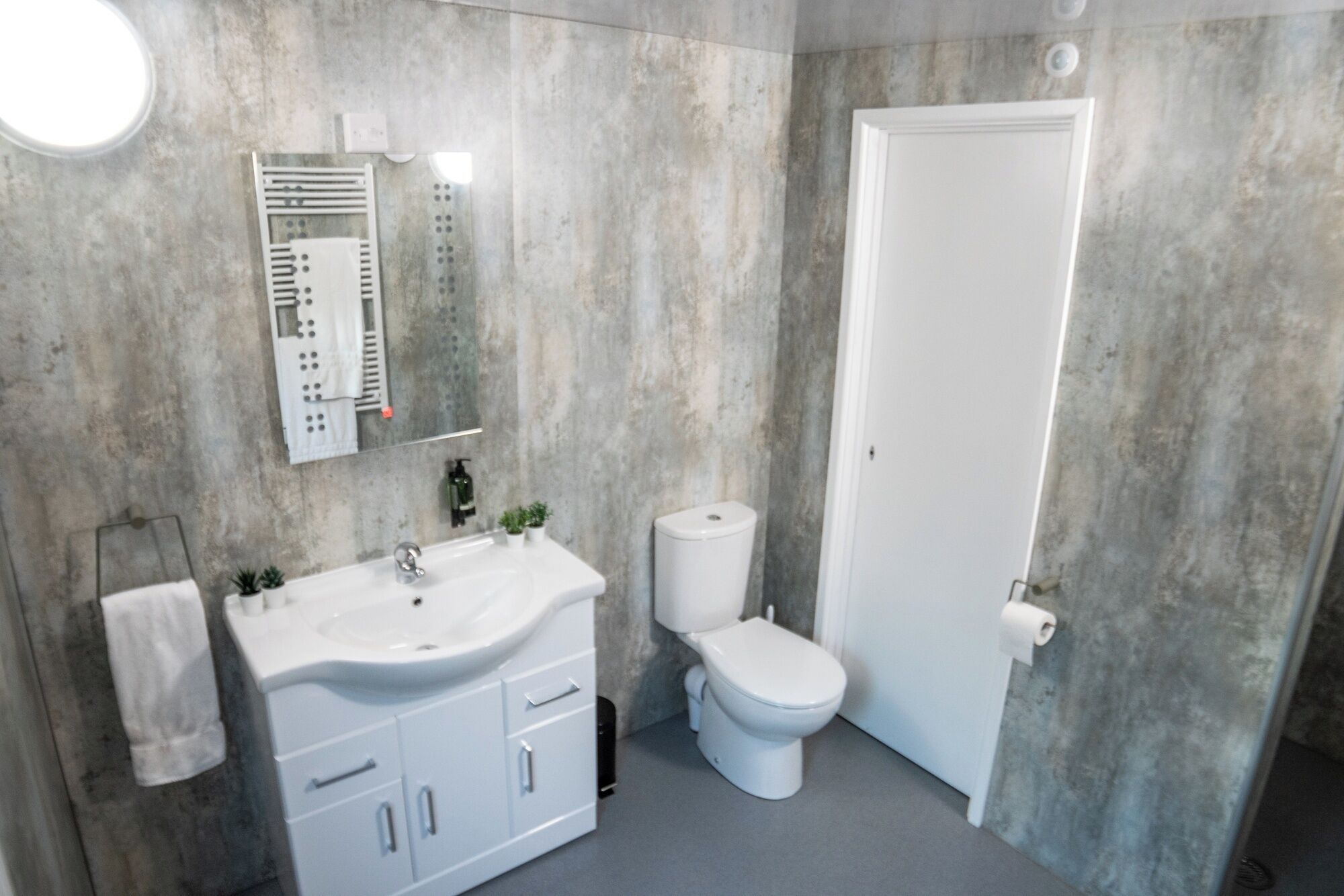 Une salle de bain avec un lavabo blanc, des toilettes et une serviette accrochée au mur.