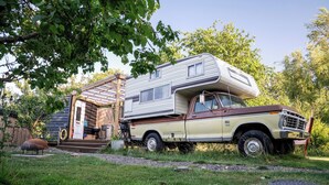 A camper van parked in front of a wooden structure with a covered porch. - 1 Bed Vehicle Luxury Camper -hot Tub, Pets - Willy (Skegness)