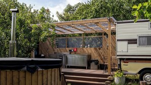 A covered outdoor area with a wooden pergola, a hot tub, and a camper van. - 1 Bed Vehicle Luxury Camper -hot Tub, Pets - Willy (Skegness)