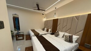 Una habitación de hotel moderna con dos camas, un ventilador de techo, lámparas colgantes y una mesita.