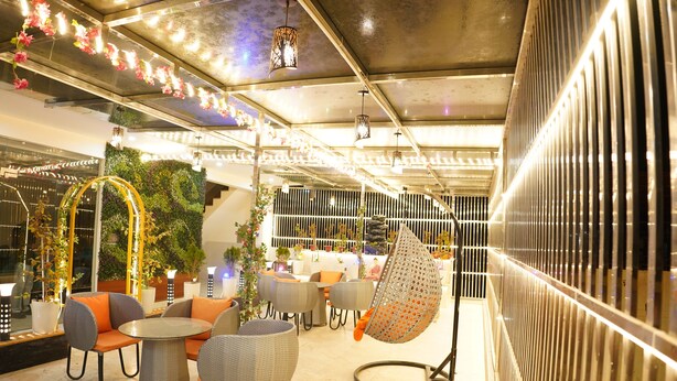 Un área de estar moderna en el interior, con mesas redondas, sillas acolchadas y una silla colgante.