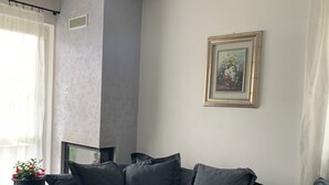 En moderne stue med en grå sofa, et lille sofabord med en plante, og et billede i ramme på væggen.
