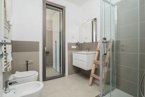 A modern bathroom with a toilet, sink, and glass shower enclosure. - 'Pascoli Suite Apartment' with Sea View, Wi-Fi and Air Conditioning (Golfo Aranci)