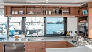 A modern kitchen with a large window, wooden cabinets, and a view of the marina.