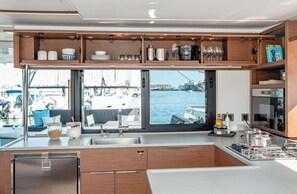Une cuisine moderne avec vue sur le port de plaisance, des meubles en bois, des appareils électroménagers en acier inoxydable et une grande fenêtre.