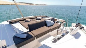 A boat's deck with a sofa, cushions, and a small table with items.