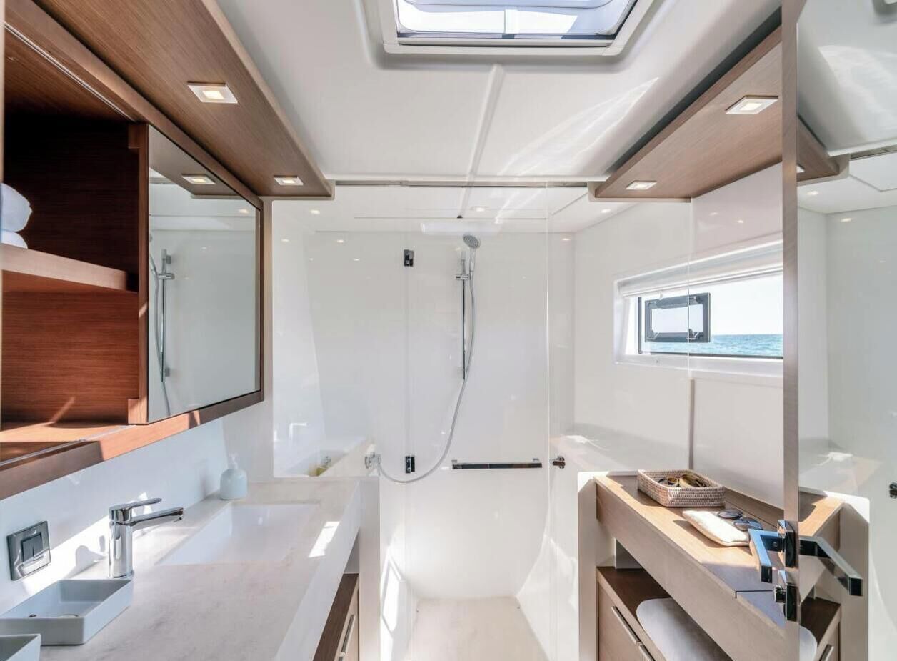 A modern bathroom with a skylight, a shower, and a vanity with a window.