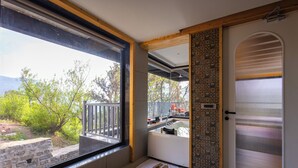 Una habitación con un ventanal grande, una puerta con diseño decorativo y vistas a espacios verdes.