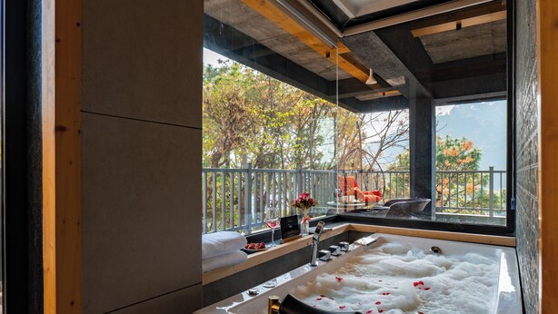 Un baño moderno con una bañera grande, una ventana con vistas a árboles y un techo de madera.