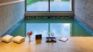 Una habitación con un gran ventanal, piscina, toallas, una bandeja con bebidas y un menú.