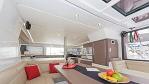 A modern interior with a dining area, kitchen, and seating. - Sun-Kissed Sailing Adventure in Islas Sarónicas (Alimos)