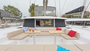 A yacht deck with a seating area, tables, and a covered section. - Sun-Kissed Sailing Adventure in Islas Sarónicas (Alimos)