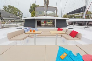 A yacht deck with a seating area, tables, and a covered section.