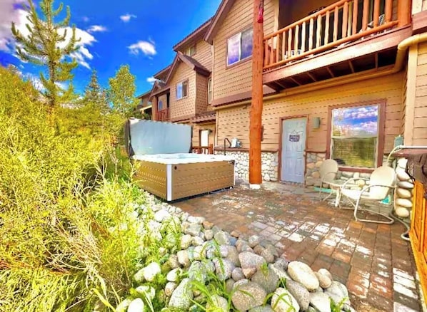 Una cabaña de madera con jacuzzi, zona de estar exterior y un sendero de piedra.