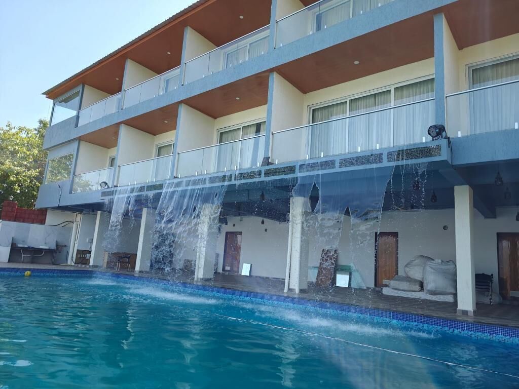 Un hotel con piscina, fuente de agua y balcones.