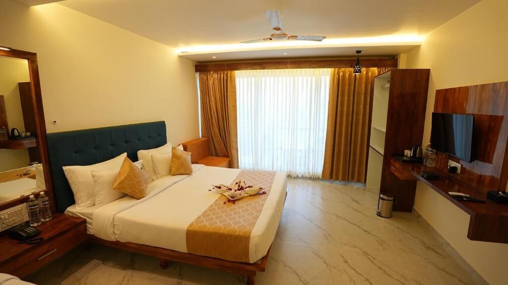 A hotel room with a large bed, a desk with a chair, a TV, and a bathroom.