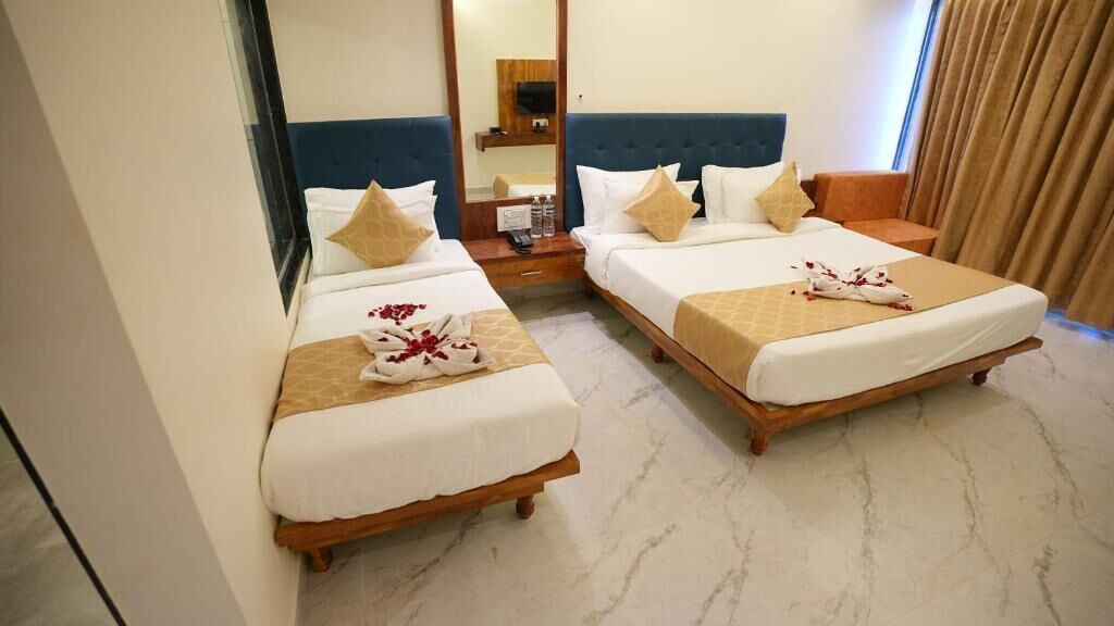 Habitación de hotel con dos camas, un espejo, una mesita de noche y una ventana con cortinas.