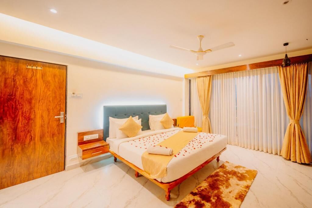A bedroom with a bed, a ceiling fan, a wooden door, and a window with curtains.
