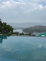 Una piscina con vistas a un río y colinas.