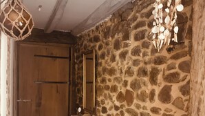 A stone wall interior with a wooden door, a small table with a mirror, and a hanging light fixture. - Nature gite (2 suites) near Espellette and Cambo les bains Pets welcome (Itxassou)