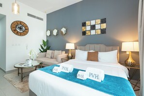 Een hotelkamer met een bed, twee nachtkastjes, een bank, een klok en decoratieve wandkunst.