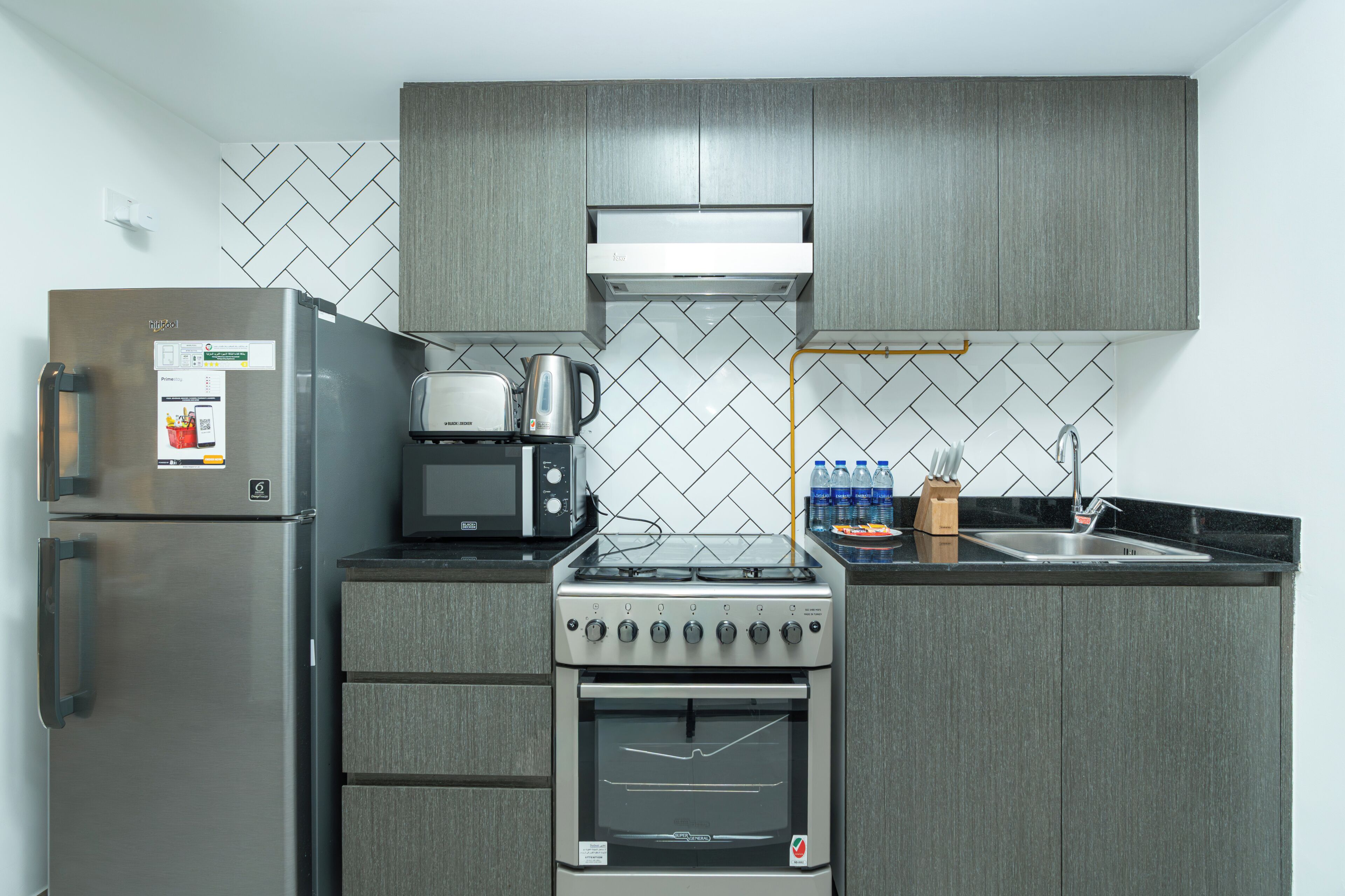 A compact kitchen with a refrigerator, microwave, toaster, stove, oven, and a sink.