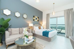 Een moderne hotelkamer met een bank, een bed, een ronde salontafel en uitzicht op de stad.