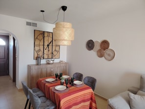 Zona pranzo con tovaglia a righe, orologio a parete e decorazioni murali in tessuto.