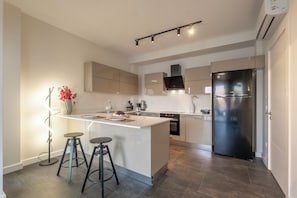 Una cocina moderna con una isla central, electrodomésticos de acero inoxidable y una lámpara colgante.