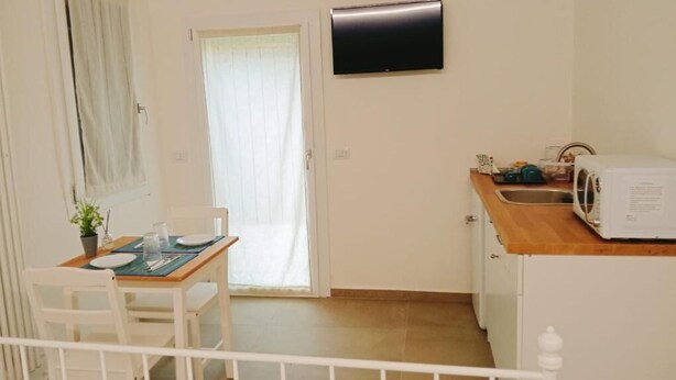 Una pequeña cocina con microondas, lavamanos y comedor con mesa y sillas.