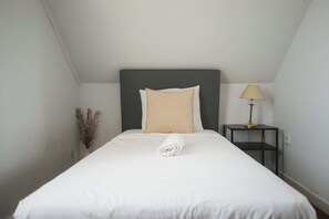 A neatly made bed with a rolled white towel, a bedside lamp, and a small plant on a nightstand. - Penha Single Bedroom, Hostel Idanha, Idanha-a-Nova (Idanha-a-Nova)