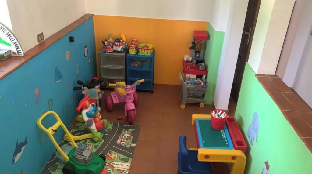 Una stanza giochi per bambini con giocattoli, scaffali e un piccolo tavolo.