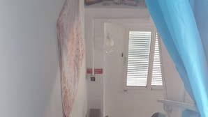 Un escalier avec un rideau bleu, une enseigne fixée au mur et une fenêtre avec des stores.