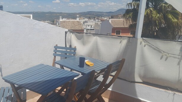 Un balcon avec une table et des chaises, un pot de fleurs et une vue sur le paysage urbain.