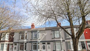 Une rangée de maisons de ville avec des bow-windows, une cheminée en briques et un arbre au premier plan.