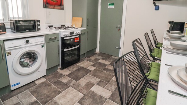 Une cuisine compacte équipée d’un lave-linge, d’un four à micro-ondes, d’une cuisinière et d’un coin repas avec des chaises.