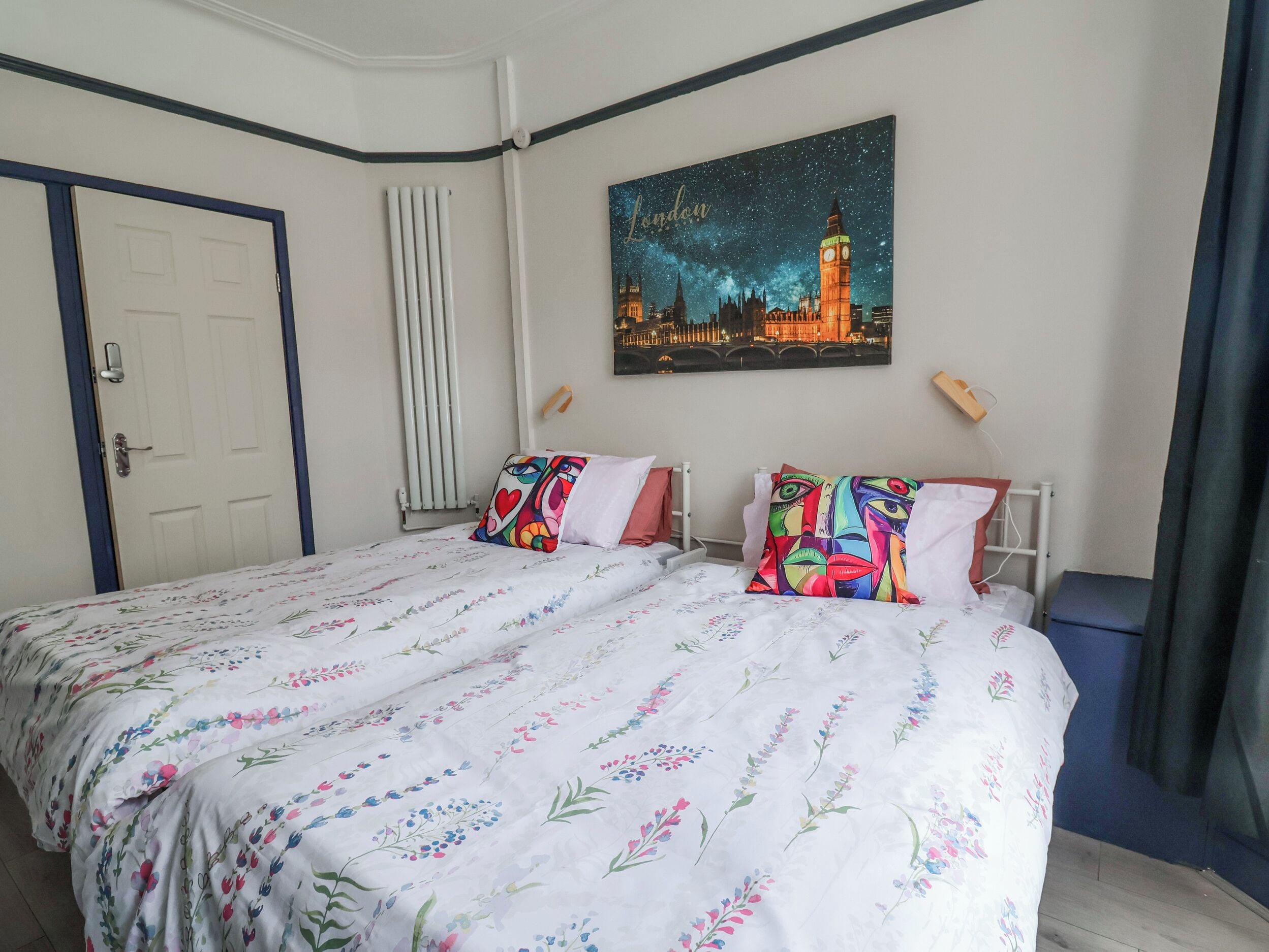 Ein Schlafzimmer mit einem Bett, einem Himmelgemälde, einem Heizkörper und einer Tür.
